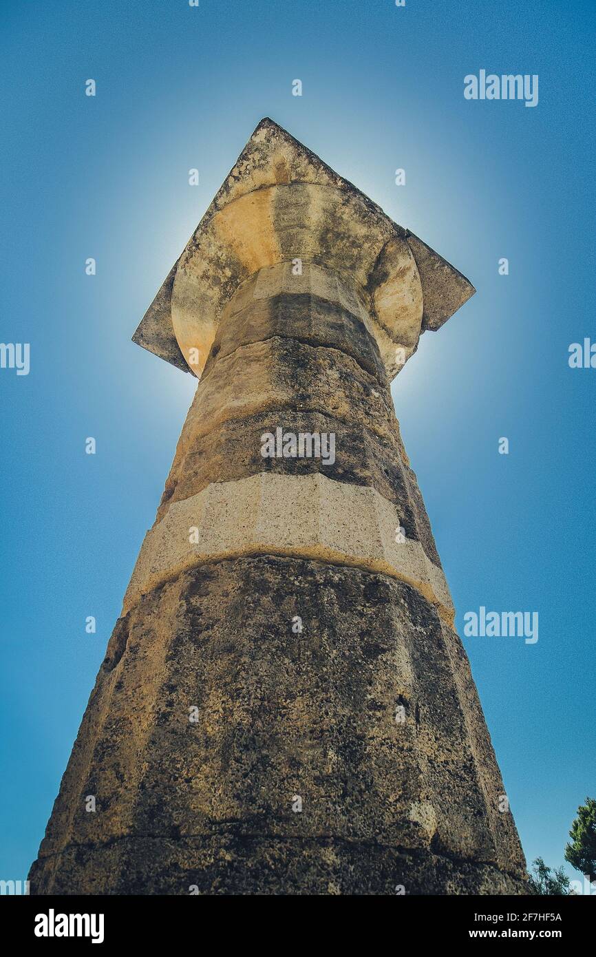 Ein vertikales Foto der dorischen Ordersäule oder Säule, aufgenommen auf der antiken archäologischen Stätte von Olympia, Griechenland, an einem sonnigen Tag mit Sonne scheint di Stockfoto