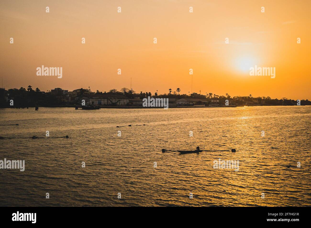 Sonnenuntergang in Ziguinchor, Afrika, beobachtet ihn von der Brücke über den casamance-Fluss in Richtung Fährhafen. Ein Fischer mit Boot und Netzen sind zu sehen Stockfoto