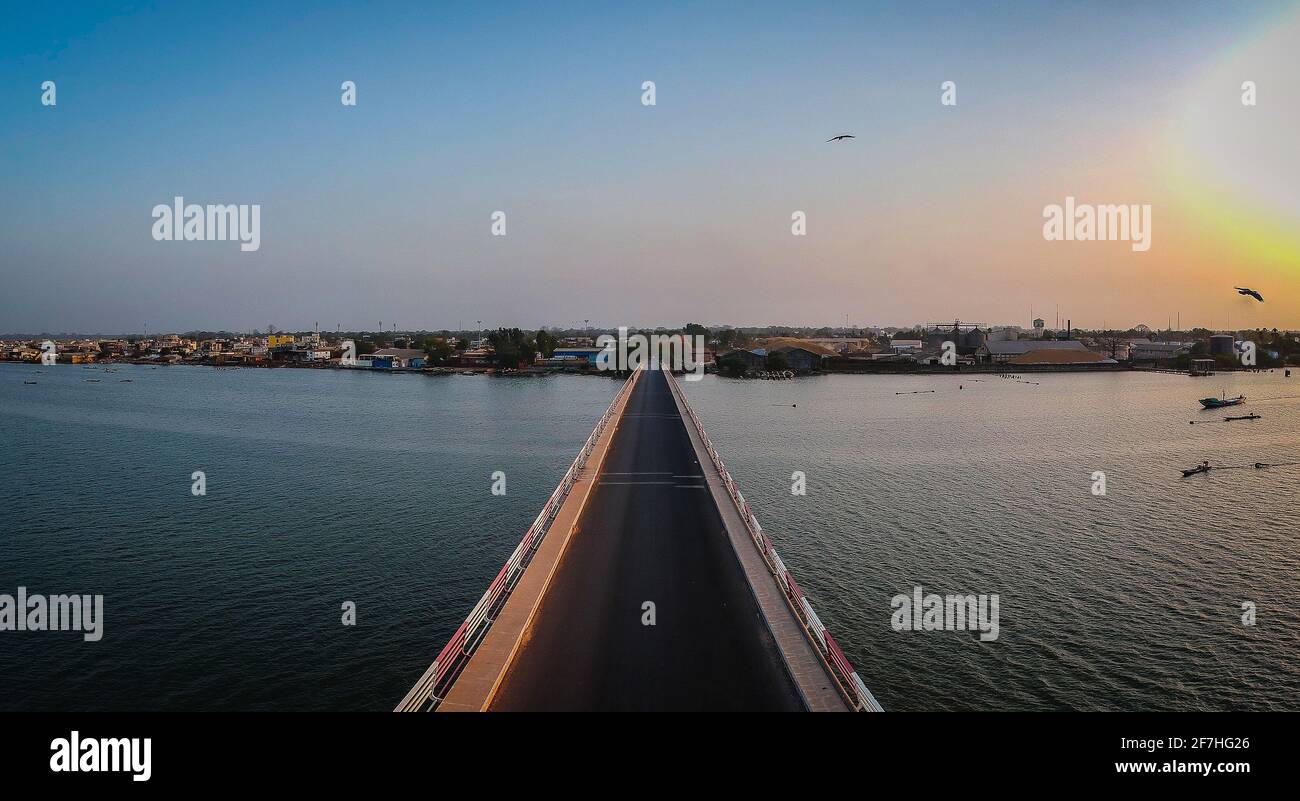 Luftaufnahme der Straßenbrücke über den fluss casamance in Ziguinchor, Senegal, Afrika bei Sonnenuntergang. Drohnenbild mit Blick auf die Stadt über dem d Stockfoto