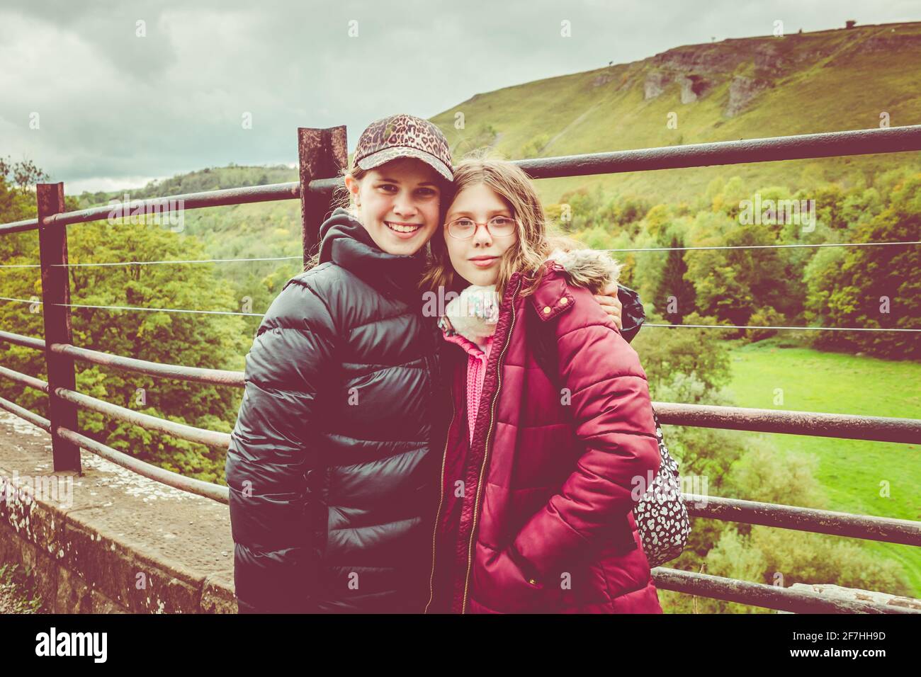 Zwei Teenager/zwei Mädchen auf einer Wanderung, die an einem kalten Tag auf dem Grabstein-Viadukt in Monsal Dale, dem Peak District, Derbyshire, wandern Stockfoto