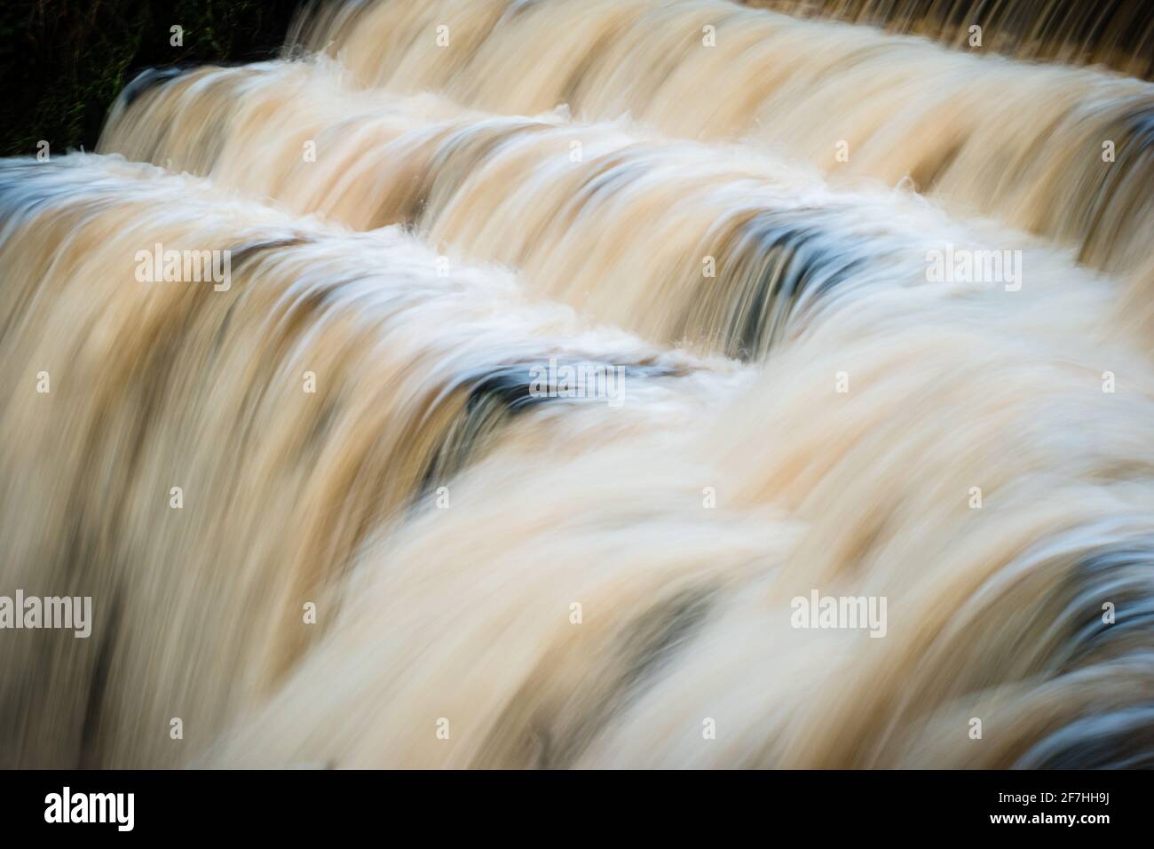 Eine lange Exposition von schnellem Wasser in einem stufenförmigen Wasserfall oder Wehr von der Seite, Konzept der Bewegung Stockfoto