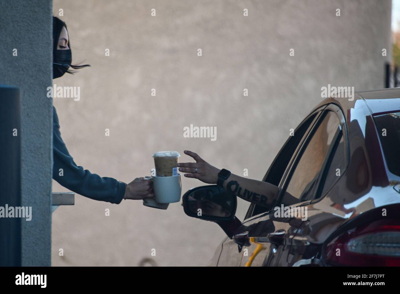 Ein Mitarbeiter von Starbucks Coffee übergibt einem Gast während der Coronavirus-Pandemie am Sonntag, den 21. Februar 2021 in Moreno Valley, Kalifornien (Dylan S Stockfoto