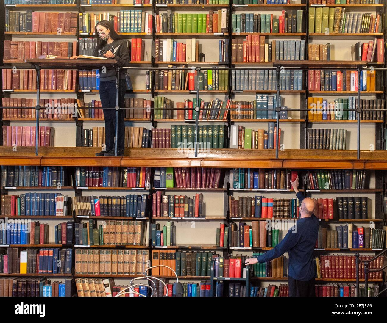 Die Mitarbeiter Saba Chaudry (oben) und Michael Booth treffen die letzten Vorbereitungen im Lesesaal der London Library am St. James Square, London, bevor die geplante Wiedereröffnung für Mitglieder am 12. April stattfindet, da die Regierung die derzeitigen Beschränkungen des Coronavirus lockert. Bilddatum: Mittwoch, 7. April 2021. Die London Library wurde 1841 gegründet und verfügt über mehr als 1,000,000 Titel, die über 2,000 Themen in 55 verschiedenen Sprachen abdecken. Die Buchreihe reicht von 1500 bis 2015, ergänzt durch gebundene Exemplare von über 2,000 Zeitschriften aus den Jahren 1699 bis heute. Stockfoto