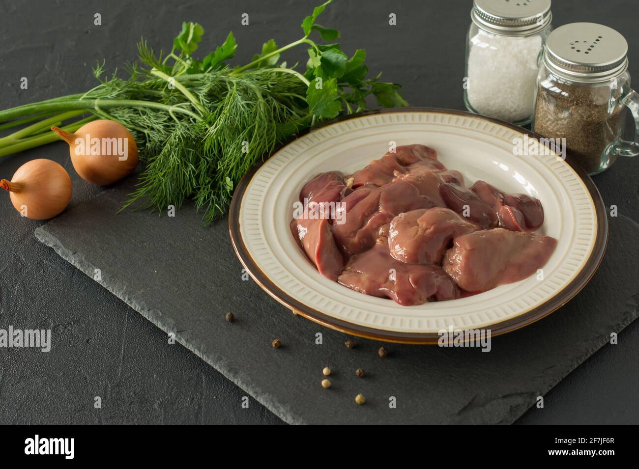 Rohe Hühnerleber in Schüssel auf schwarzem Hintergrund. Zutaten zum Kochen. Stockfoto