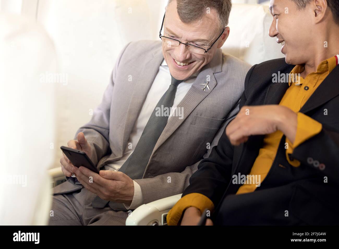 Geschäftsmann mit Sitz in Anzug über das Smartphone im Flugzeug Stockfoto