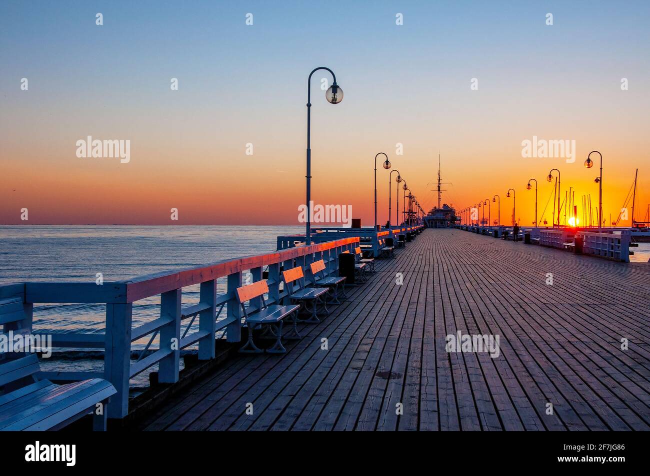 Sonnenaufgang am hölzernen Pier namens Molo in Sopot, Polen mit Sonneneinstrahlung auf Bänken Stockfoto