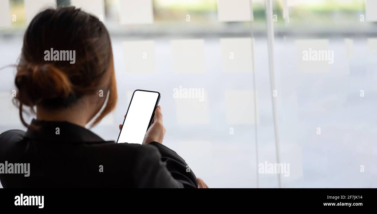 Nahaufnahme einer Geschäftsfrau mit einem Smartphone mit weißem Rohling Bildschirm im Büro Stockfoto