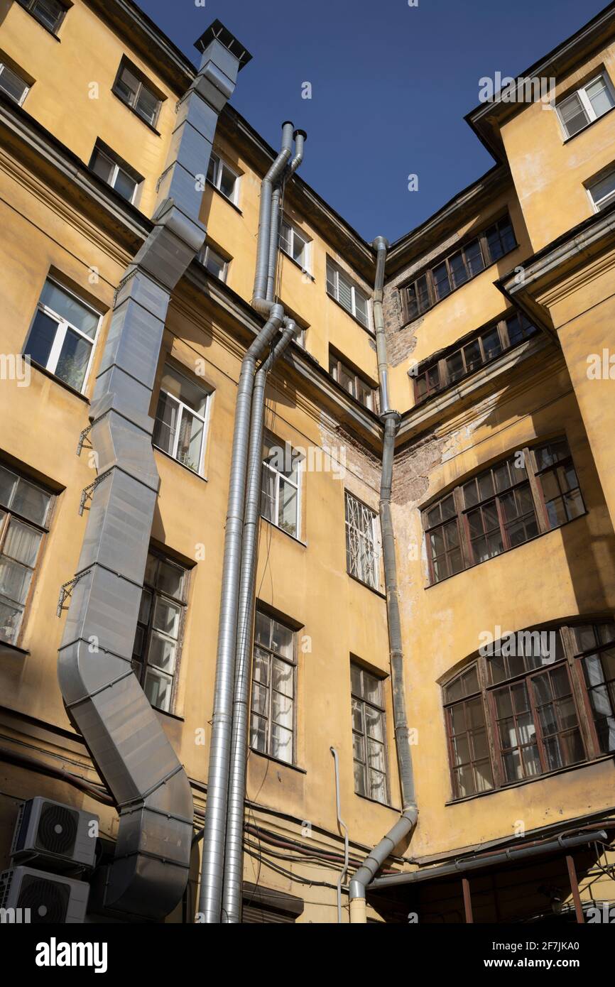 Ecke eines alten gelben Hauses mit Belüftung und Kamin Systeme und Fenster Stockfoto