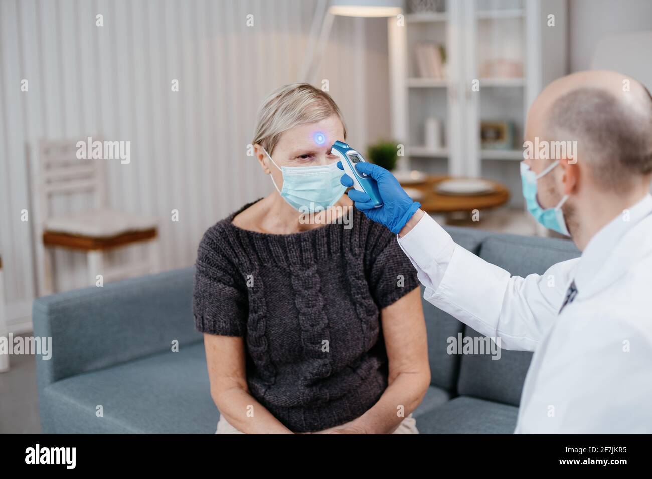 Hausarzt, der die Temperatur einer reifen Frau misst. Stockfoto