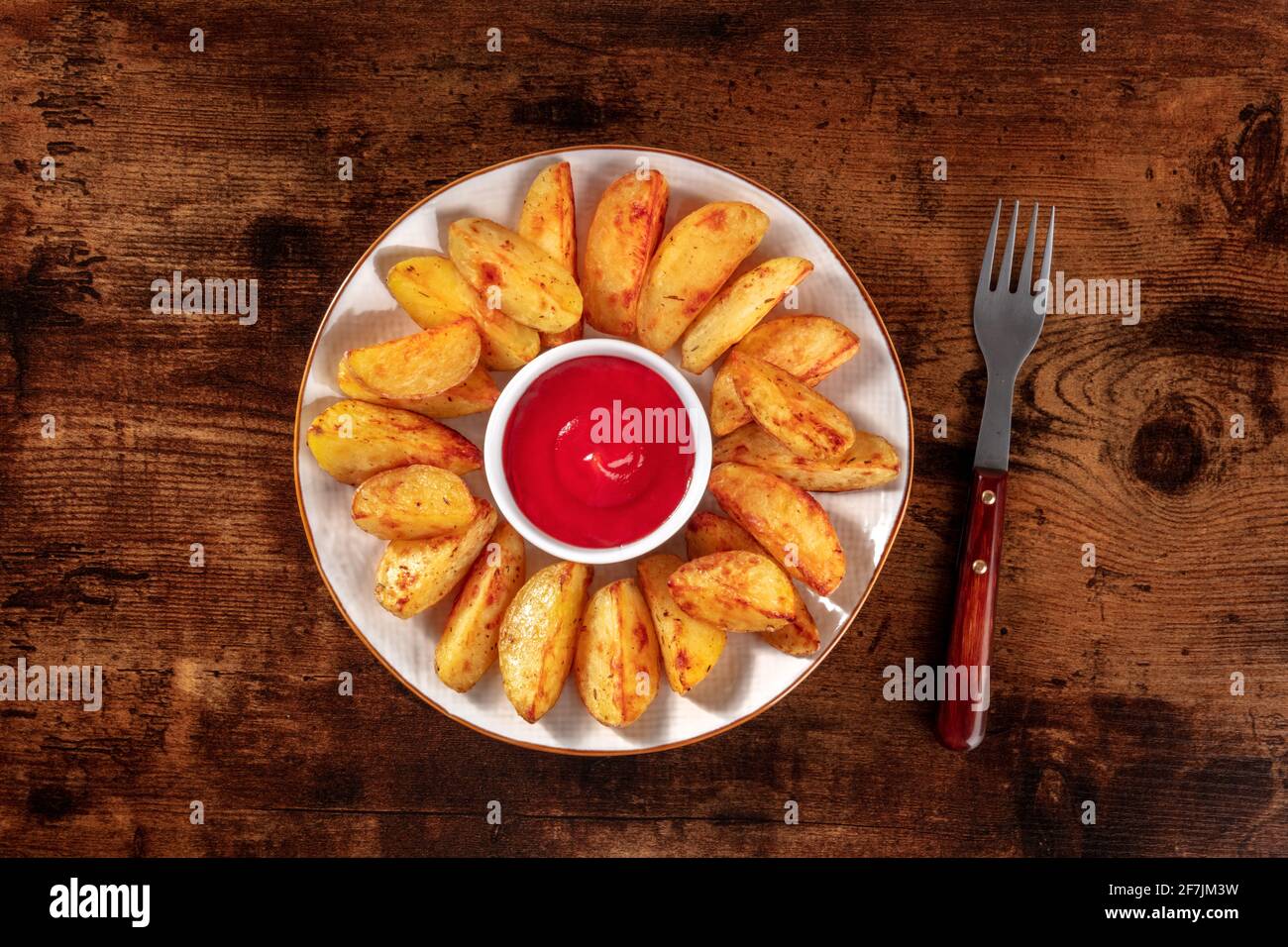 Gebackene Kartoffelkeile, von oben mit Ketchup geschossen Stockfoto