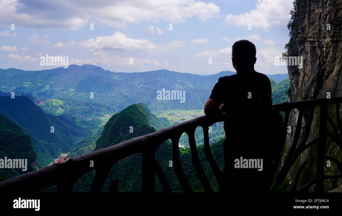 Ein Mann, der stand und den Blick auf Zhangjiajie mit grünen Bergen und blauem Himmel schaute. Stockfoto