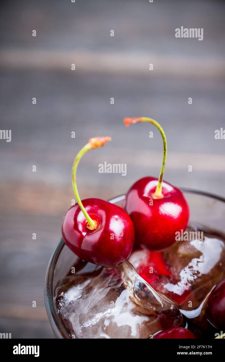 Erfrischende kalte Cherry Cola auf dem Holzhintergrund. Selektiver Fokus. Stockfoto