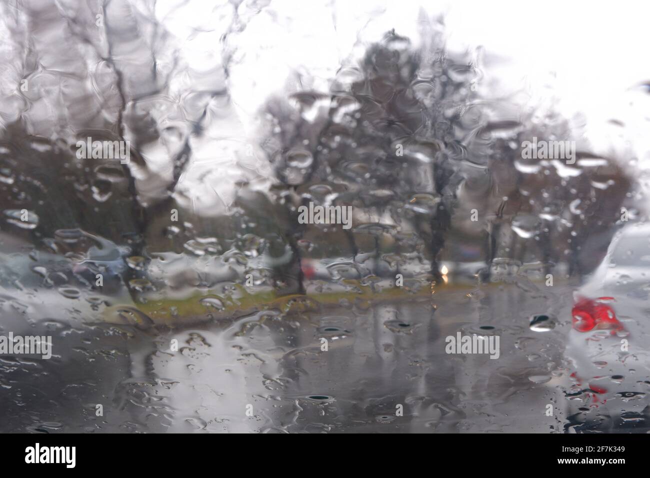 An einem regnerischen Tag fällt Wasser auf das Fenster, Verkehr auf nassen Straßen Stockfoto
