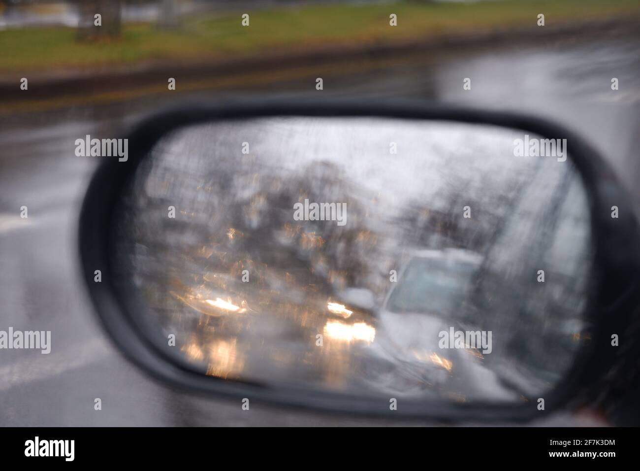 Blick vom Rückspiegel an einem regnerischen Tag mit Wasser Tropfen Stockfoto