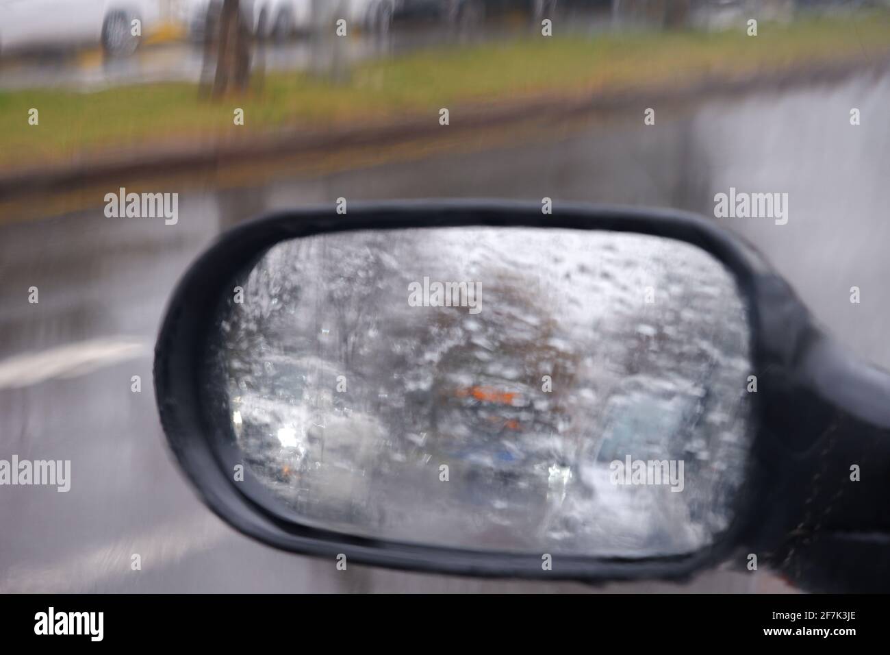 Blick vom Rückspiegel an einem regnerischen Tag mit Wasser Tropfen Stockfoto