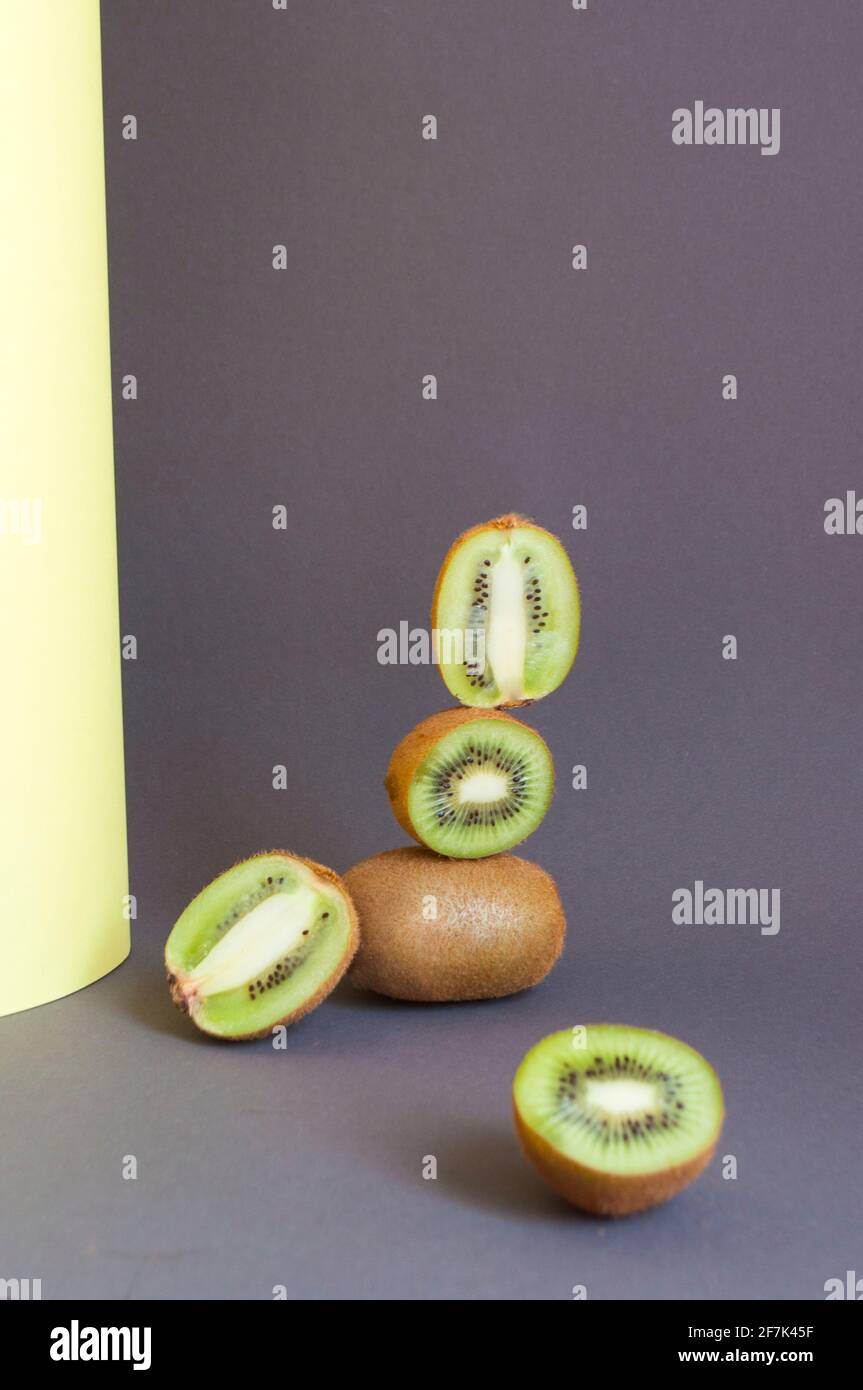 Frische grüne, saftige Kiwi-Früchte und Früchte auf ultimativem, grauem und iluminatingelbem Grund. Gleichgewicht schwimmende Lebensmittel Konzept. Stockfoto