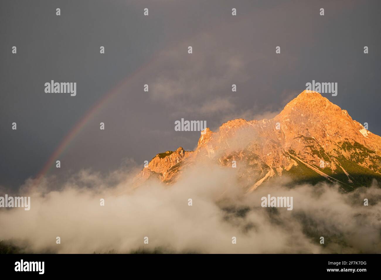 regenbogen über Berggipfel nach Regen bei Sonnenuntergang Stockfoto