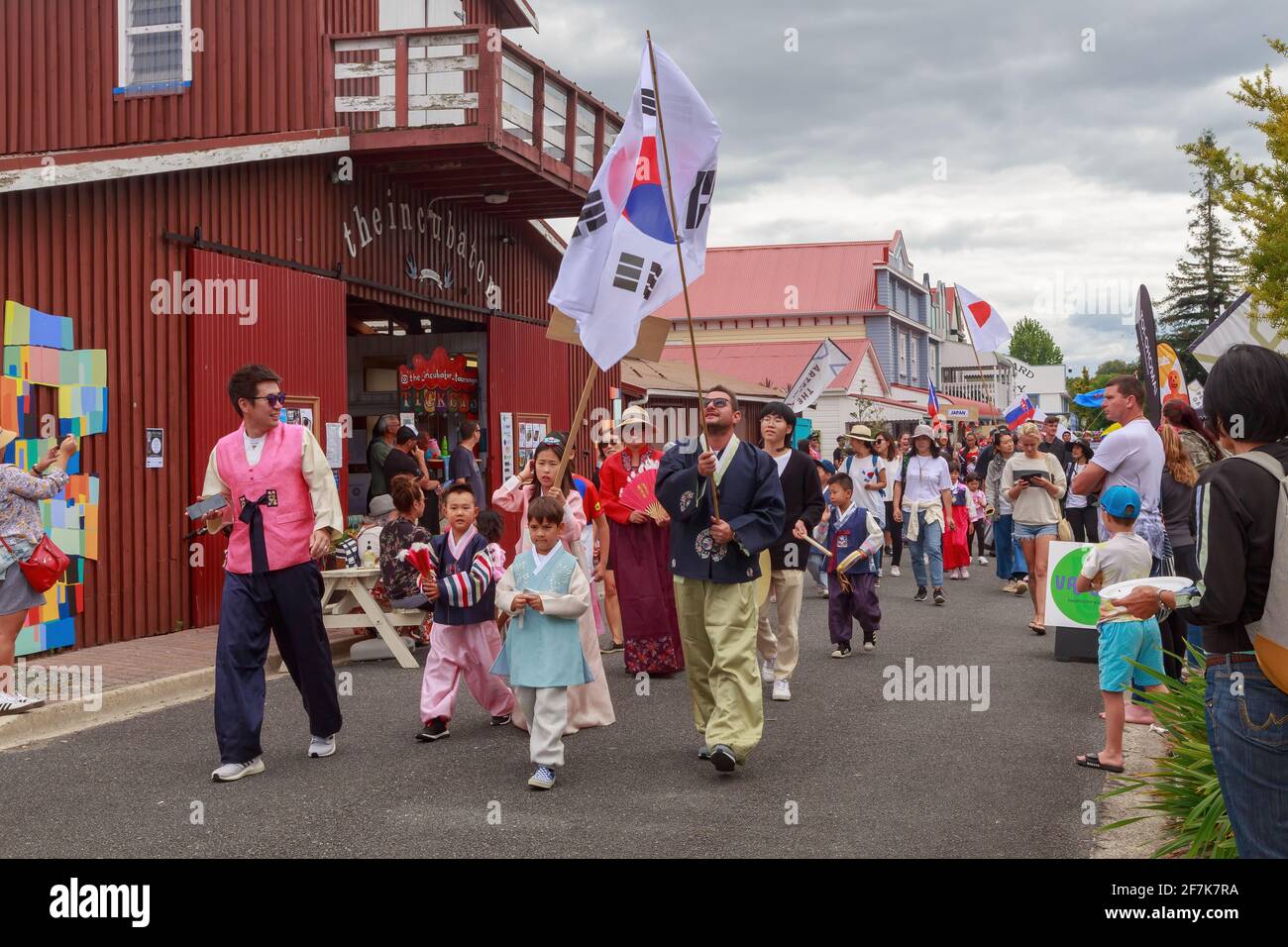 Menschen in koreanischem Volkstracht, die eine südkoreanische Flagge tragen, nehmen an einer multikulturellen Parade Teil. Tauranga, Neuseeland Stockfoto