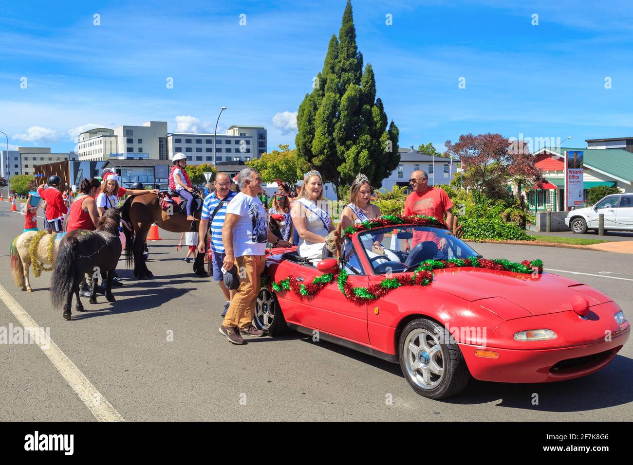 Eine Weihnachtsparade in Rotorua, Neuseeland. Zwei Schönheitsköniginnen, „Mrs. Neuseeland“ und „Miss Teen New Zealand“, die in einem dekorierten Auto fahren Stockfoto