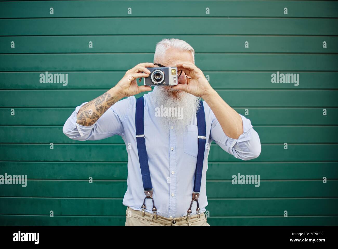 Glücklicher kaukasischer Hipster-Mann mit alter Vintage-Kamera, auf der er stand Green Wall - Reife stilvolle Fotograf mit Spaß reisen die Welt - freudige elde Stockfoto