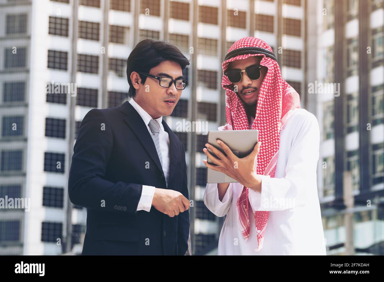Arabischer Mann und Geschäftsmann diskutieren Inhalte auf dem Tablet-Computer. Multikulturelles internationales Treffen auf dem Seeweg. Stockfoto