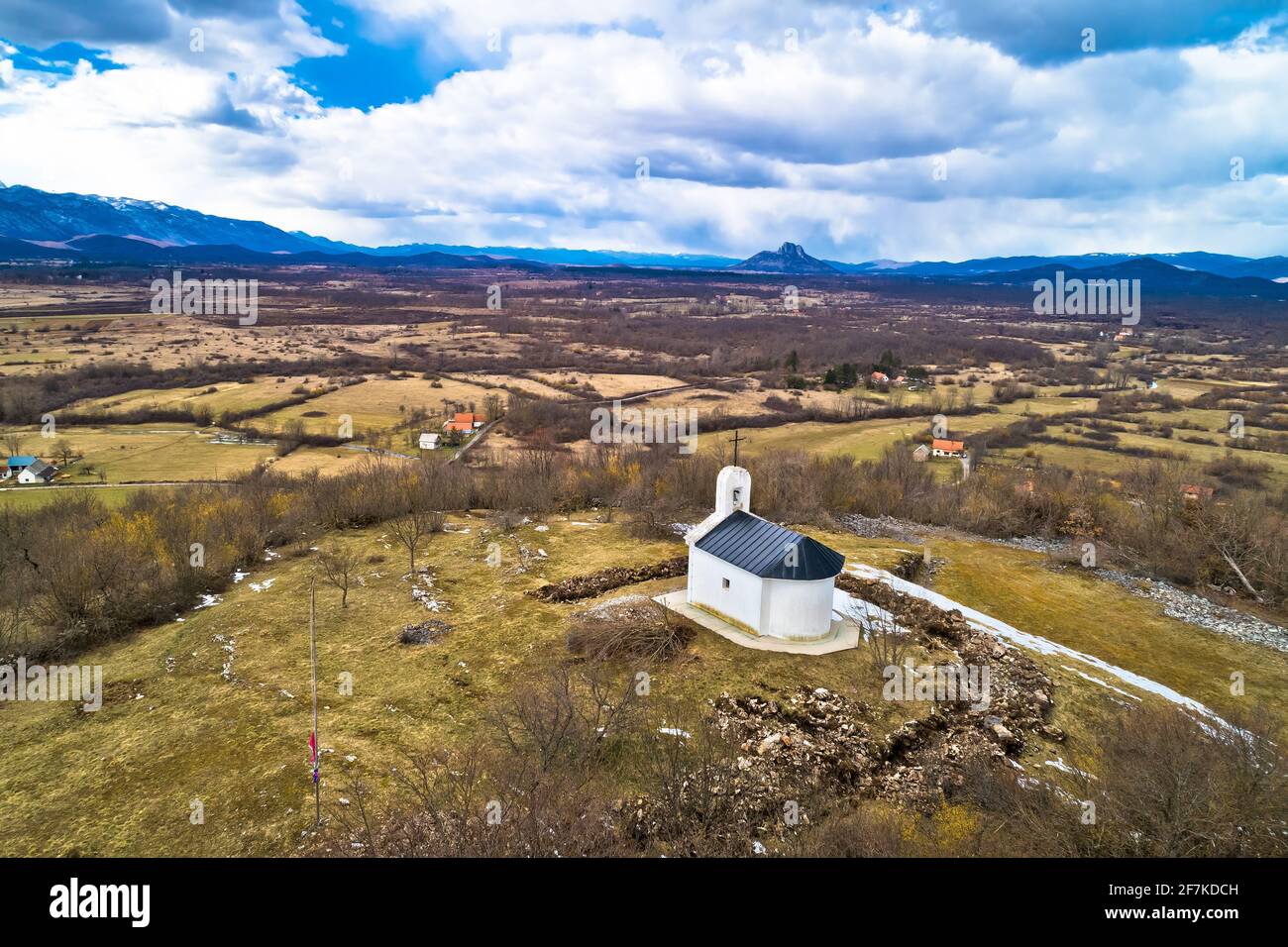 Lika-Region. Kirche auf dem Hügel in Lovinac und Velebit Berg in Lika Landschaft Luftbild. Ländliches Kroatien Stockfoto
