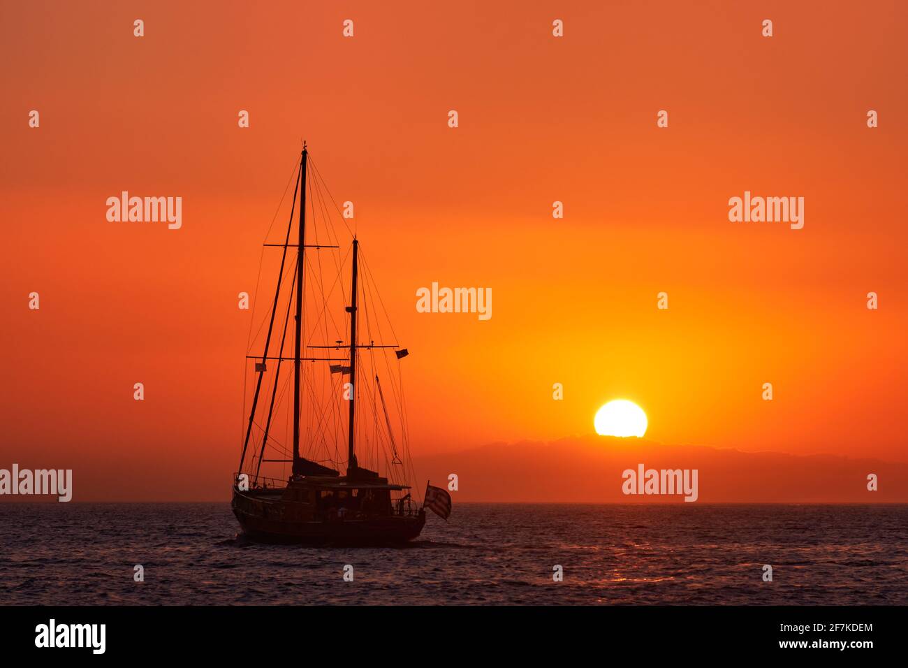 Silhouette eines Segelbootes mit Segeln gegen die Sonne bei Sonnenuntergang, Sonneneinstrahlung auf das Meer. Romantische Meereslandschaft. Urlaub Lifestyle Landschaft Stockfoto