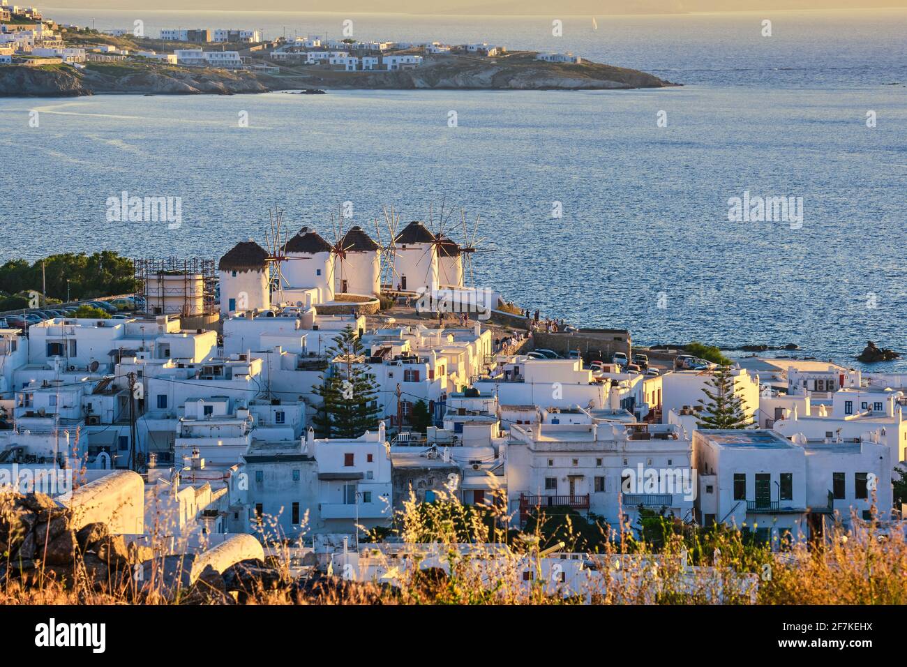 Wunderschöne Aussicht auf die berühmten traditionellen weißen Windmühlen bei Sonnenuntergang, Mykonos, Griechenland. Weiß getünchte Häuser, verschwommener Sommerabend, mediterraner Lebensstil Stockfoto