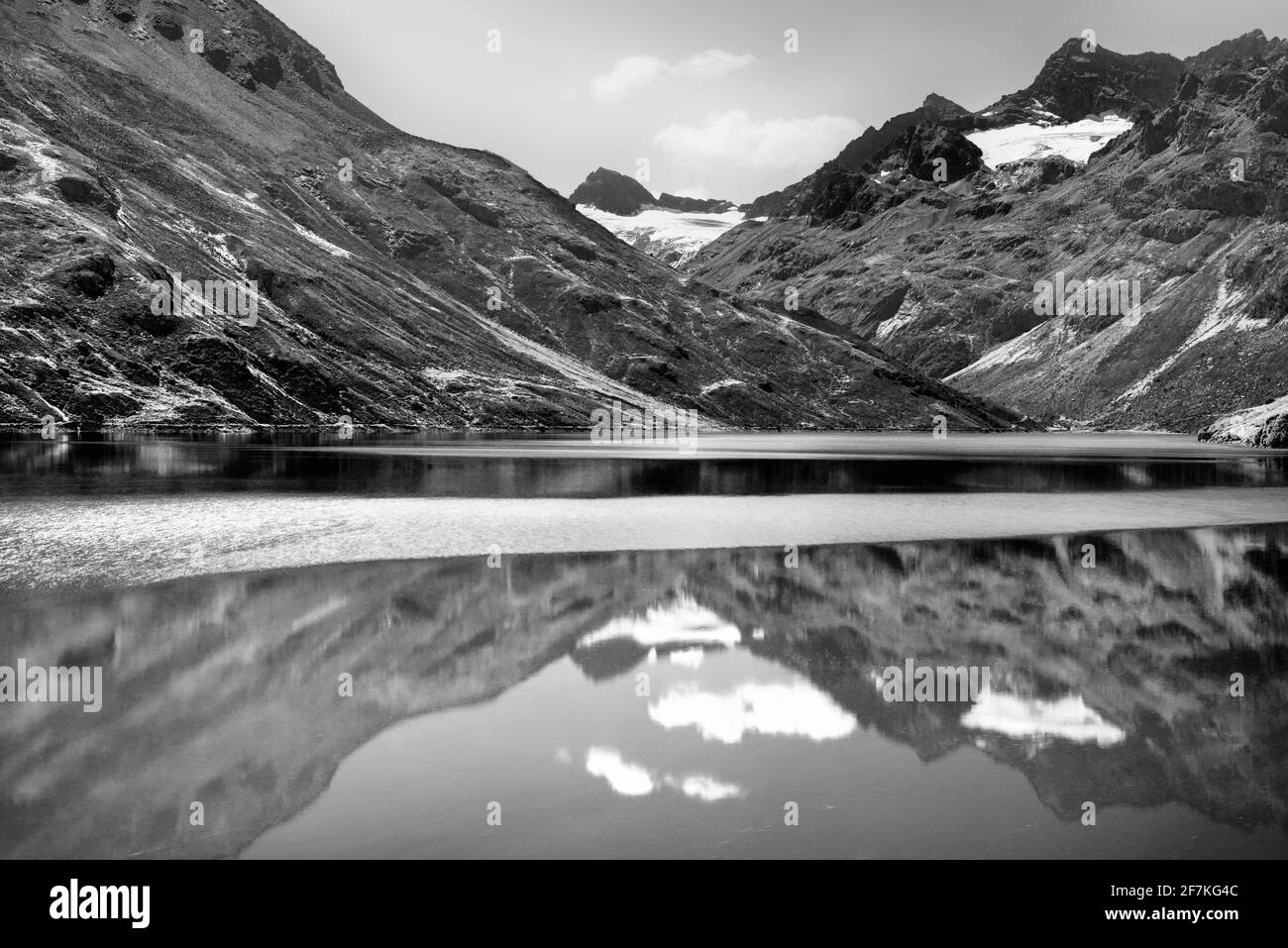 Malerische Alpenlandschaft mit See, Bergen und Gletscher. Reflexionen in einem ruhigen Bergsee. Schwarzweiß-, Schwarzweiß- und Schwarzweißfotografie. Stockfoto