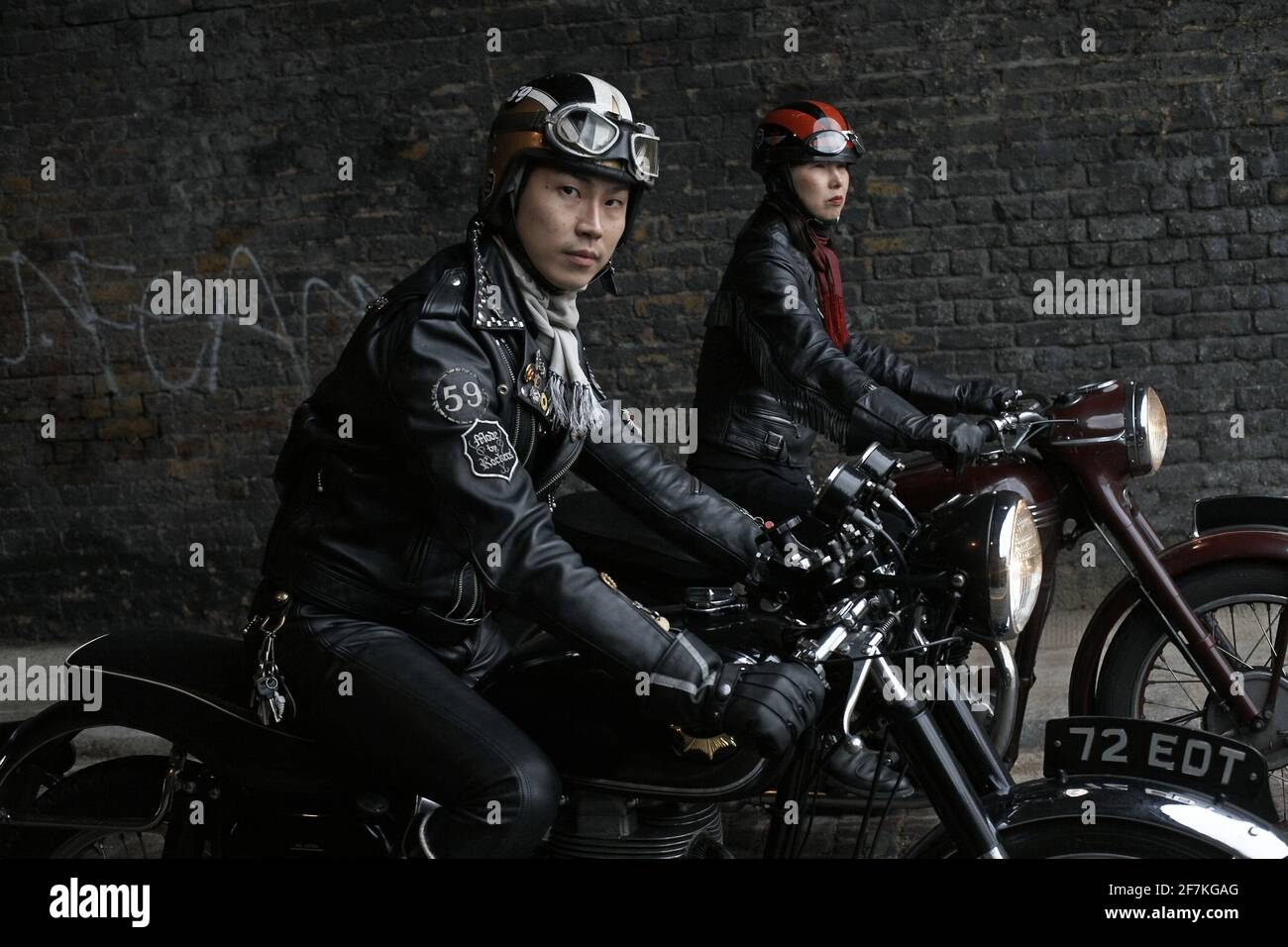Männliche und weibliche Biker, Cafe Racer trägt schwarze Lederjacken auf klassischen britischen Motorrad in London, Großbritannien sitzen Stockfoto