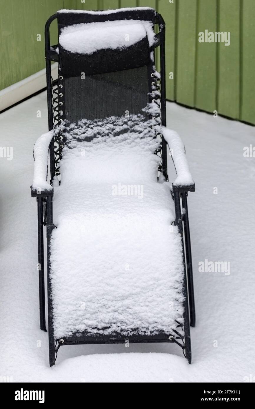 Moderne Sonnenliege oder Klappstuhl im Freien mit frischem Schnee bedeckt Stockfoto