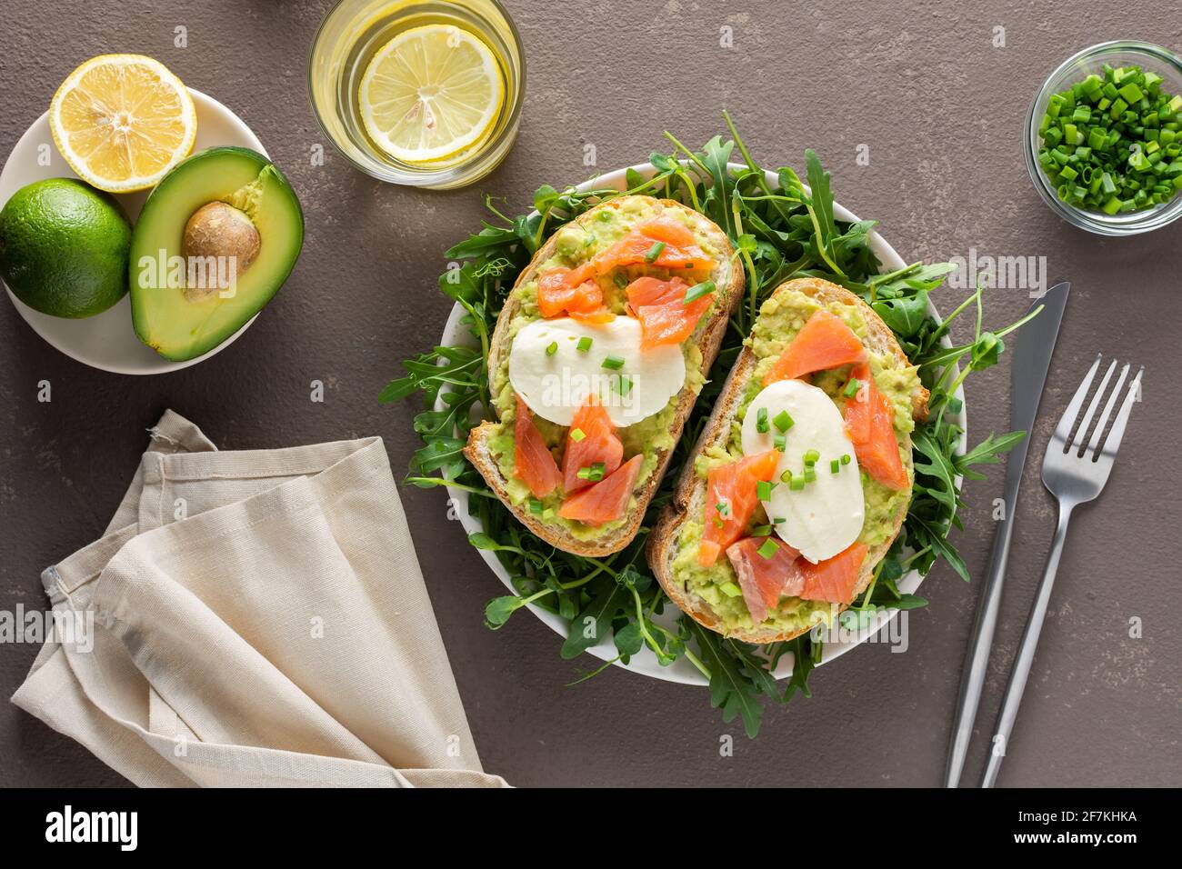 Leckeres herzhaftes Frühstück, Sandwiches mit Avocado-Paste, Lachs und Mozzarella auf einem Teller mit Rucola und Erbsensprossen Stockfoto