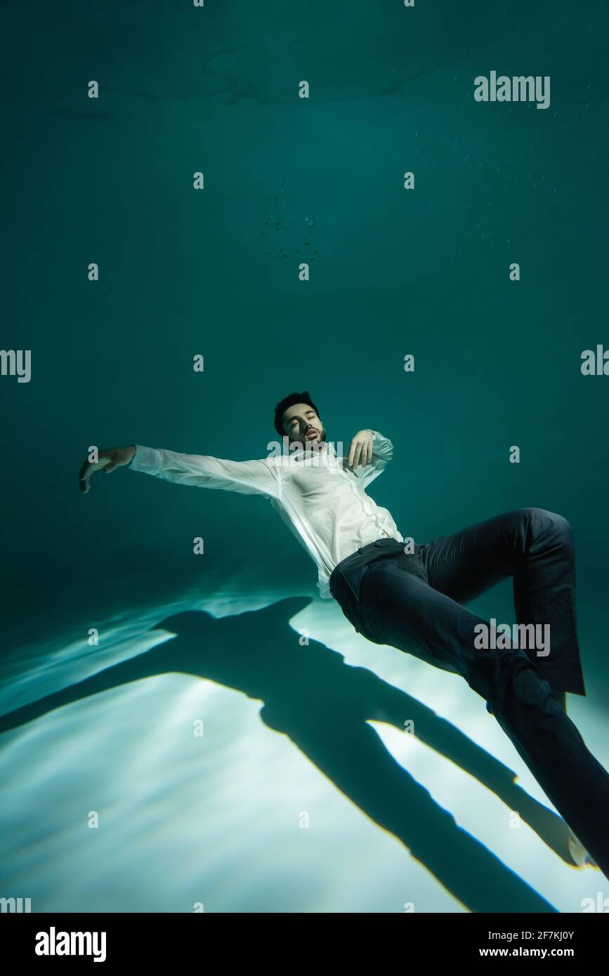 Arabischer Geschäftsmann im weißen Hemd, der im Pool schwimmend ist Stockfoto