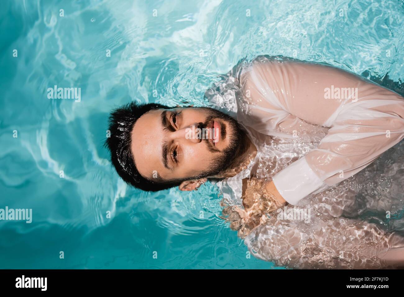 Draufsicht auf den muslimischen Geschäftsmann im Hemd, der im Pool schwimmte Stockfoto