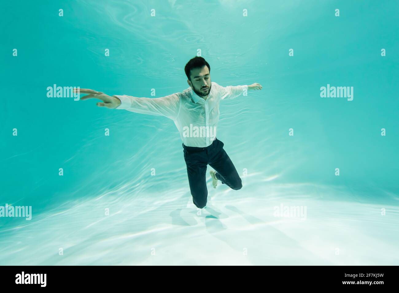 Muslimischer Geschäftsmann im Hemd, der im Schwimmbad taucht Stockfoto