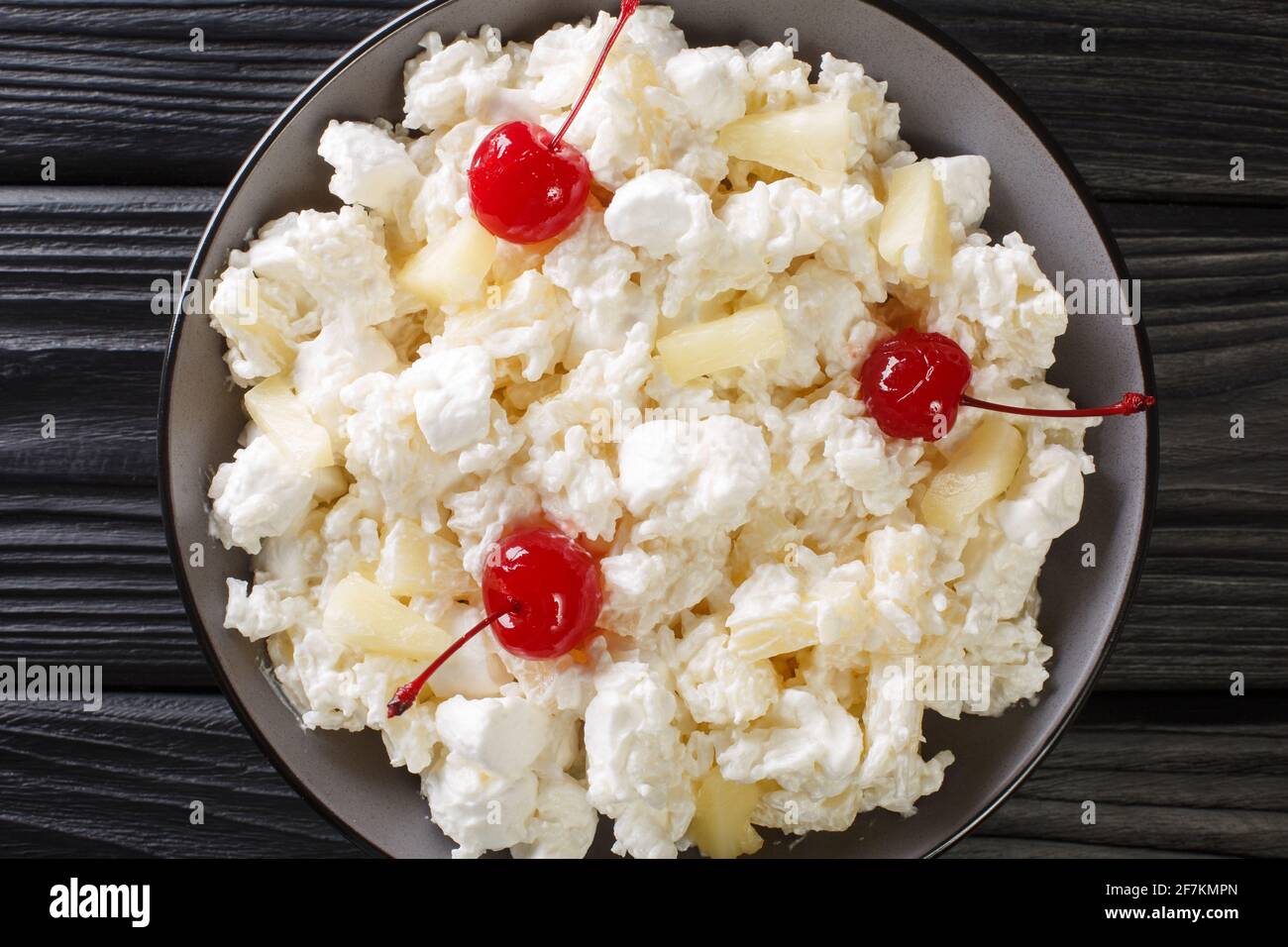 Amerikanischer Dessertsalat bestehend aus Reis, Marschmalchen und Ananas, gekleidet mit Schlagsahne aus nächster Nähe auf einem Teller auf dem Tisch. Horizontale Ansicht von oben Stockfoto