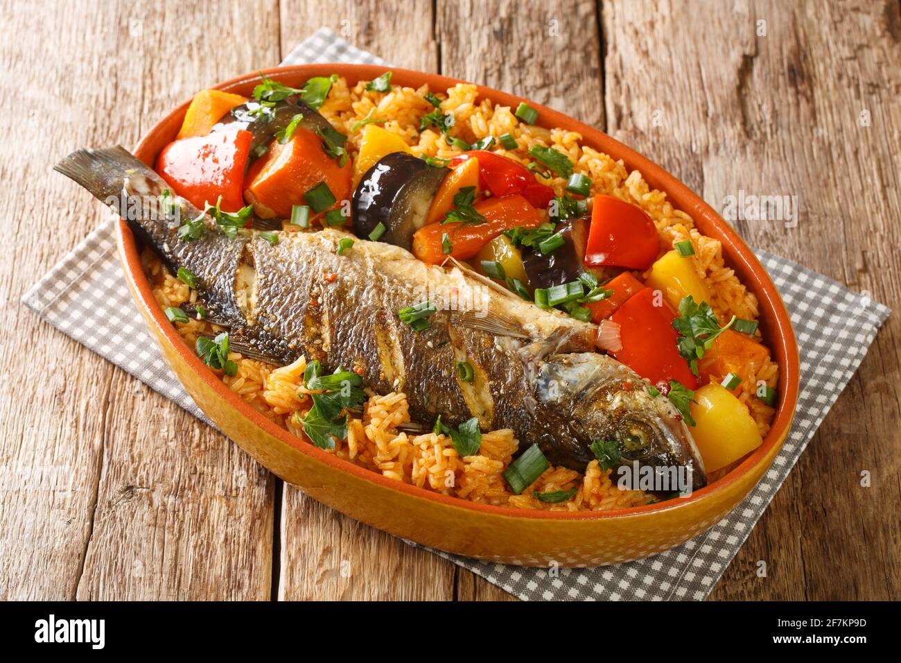 Senegalesisches Essen Thieboudienne kochte Reis und Fisch mit Gemüse aus der Nähe in einem Gericht auf dem Tisch. Horizontal Stockfoto
