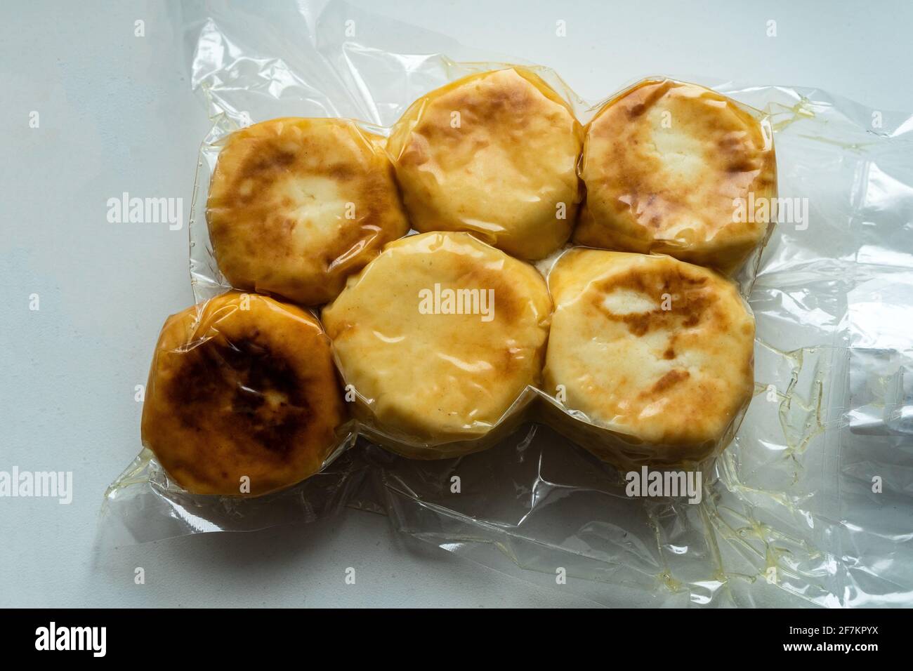 Quark-Pfannkuchen, Syrniki, Pfannkuchen mit Ricotta in Form eines gefrorenen Halbprodukts in einem Vakuumpaket. Pfannkuchen Im Handumdrehen Stockfoto