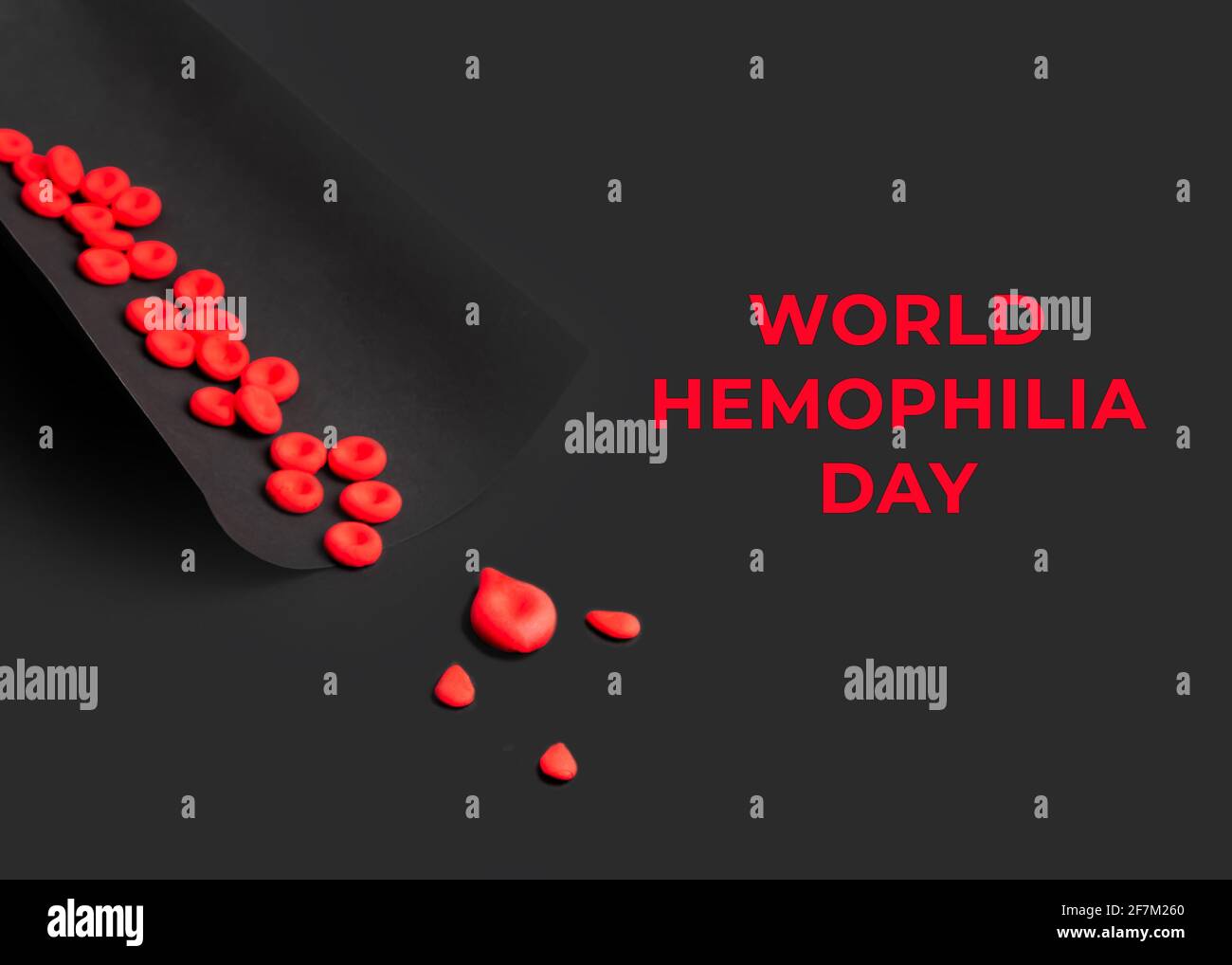 Konzept des Tages der Hämophilie. Rote Blutkörperchen und Bluttropfen werden aus Plastilin-Ton auf schwarzem Hintergrund hergestellt. Stockfoto