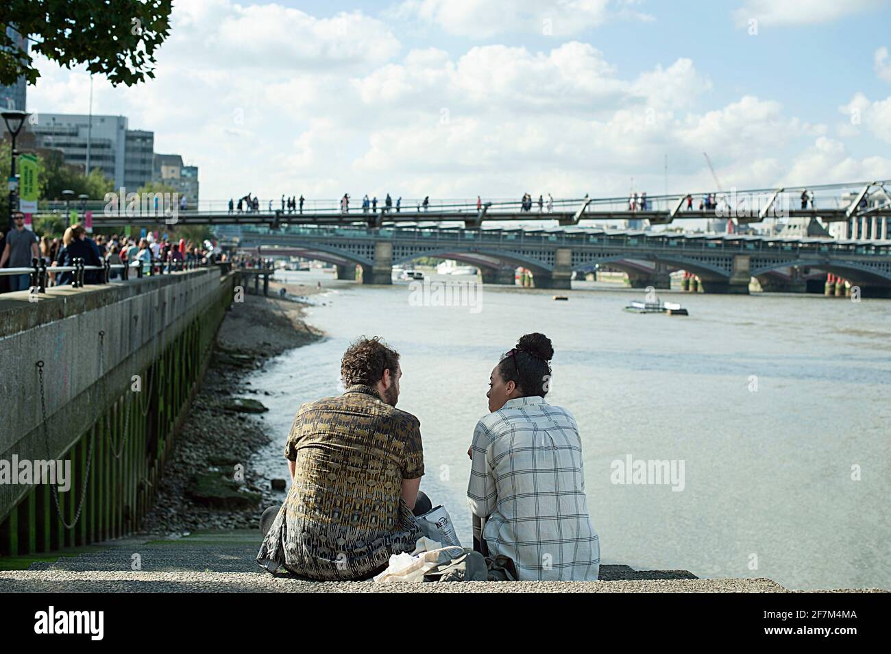 Rückansicht von 30-jährigen jungen Freunden oder Paaren, die an der Treppe, Bankside, sprachen. Ikonische Lage mit der Millennium-Brücke, Themse, London, Großbritannien Stockfoto