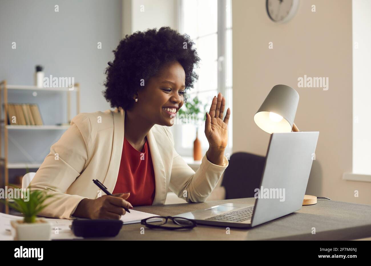 Eine freundliche afroamerikanische Geschäftsfrau hält ein Online-Meeting ab, während sie im Büro sitzt. Stockfoto