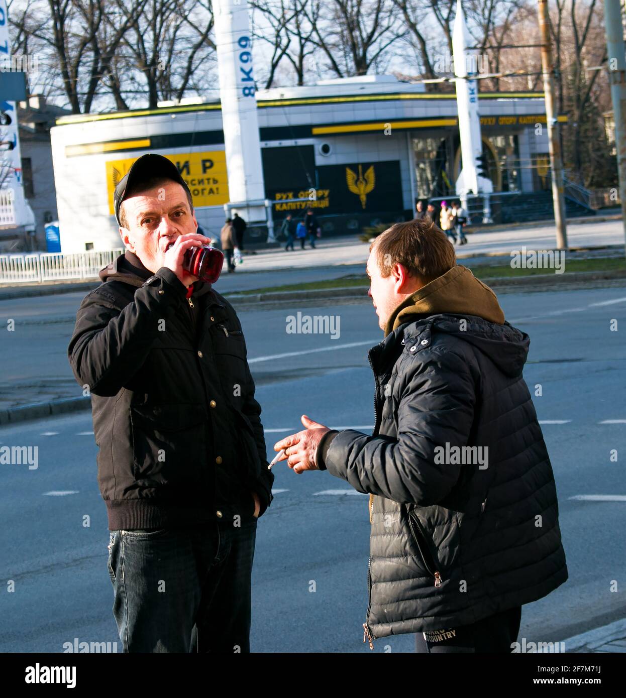 Dnepropetrovsk, Ukraine - 03.21.2021: Ein Mann trinkt Alkohol aus einer Flasche auf der Straße. Zwei obdachlose Männer fanden eine Flasche mit den Überresten von Alkohol i Stockfoto