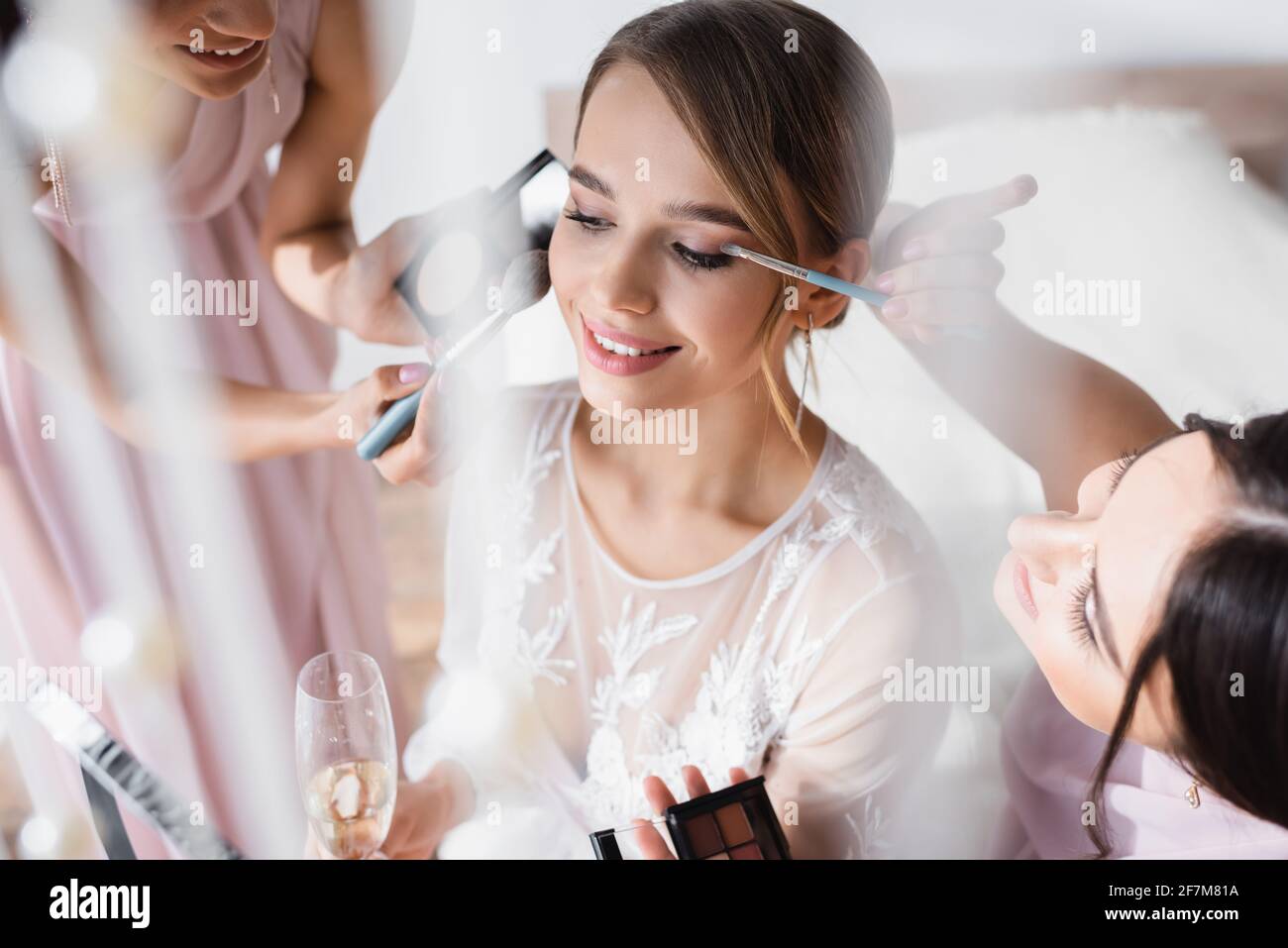Interracial Frauen Make-up zu jungen Braut mit Champagner-Glas Im unscharfen Vordergrund Stockfoto