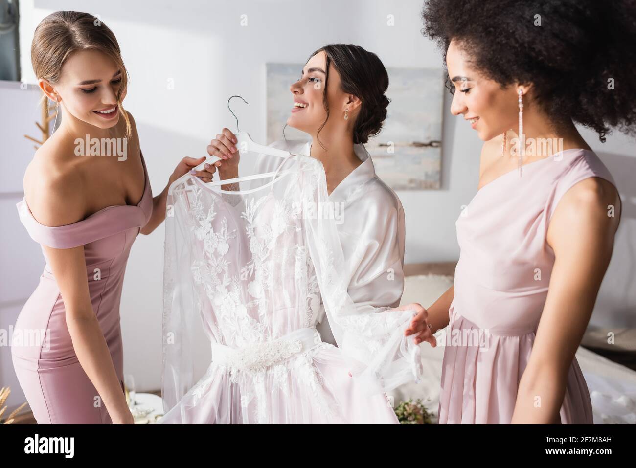 Interracial Brautjungfern mit weißen Brautkleid in der Nähe freudige Frau Stockfoto