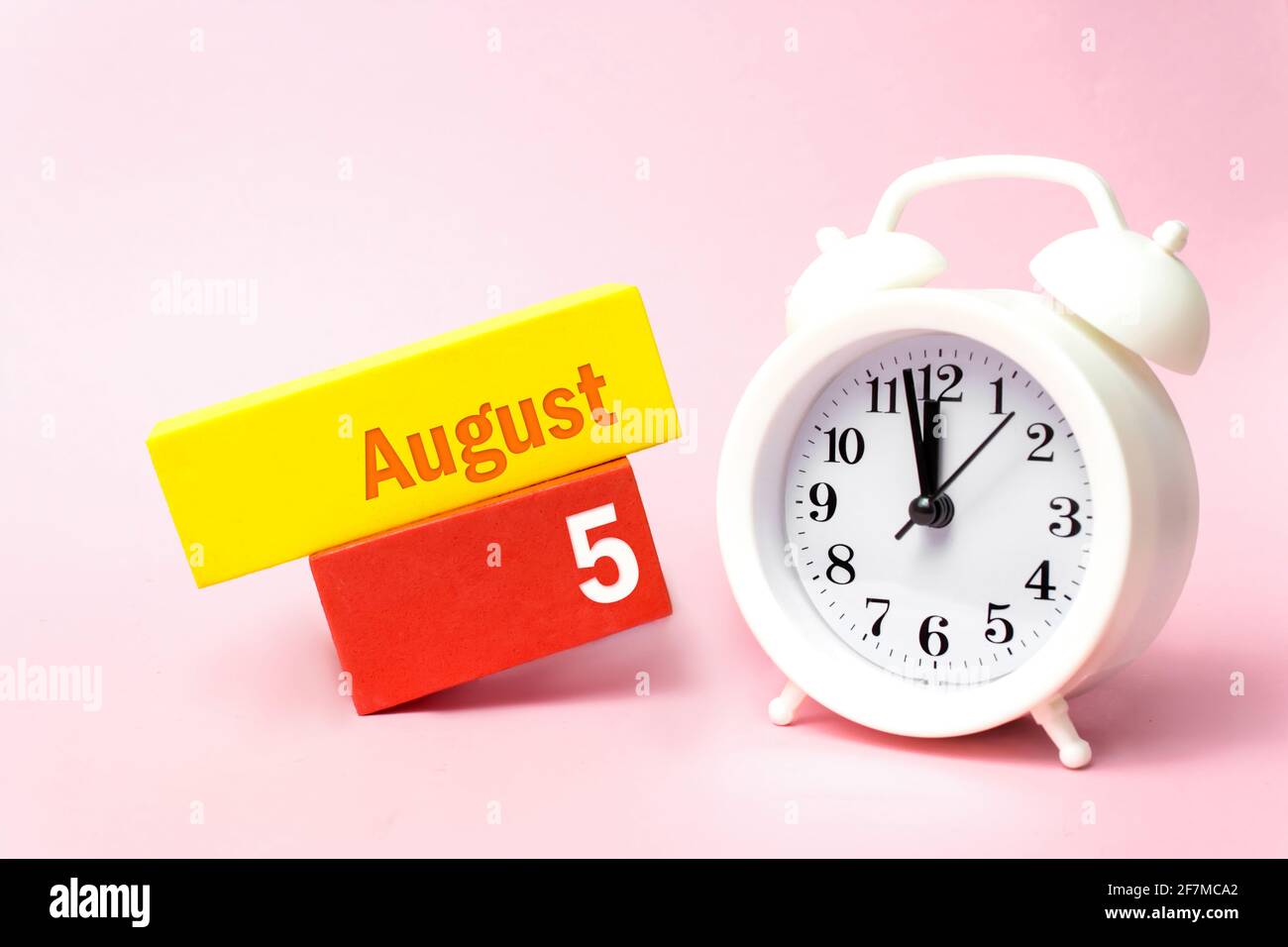 August. Tag 5 des Monats, Kalenderdatum. Weißer Wecker auf pastellrosa Hintergrund. Sommermonat, Tag des Jahres Konzept Stockfoto