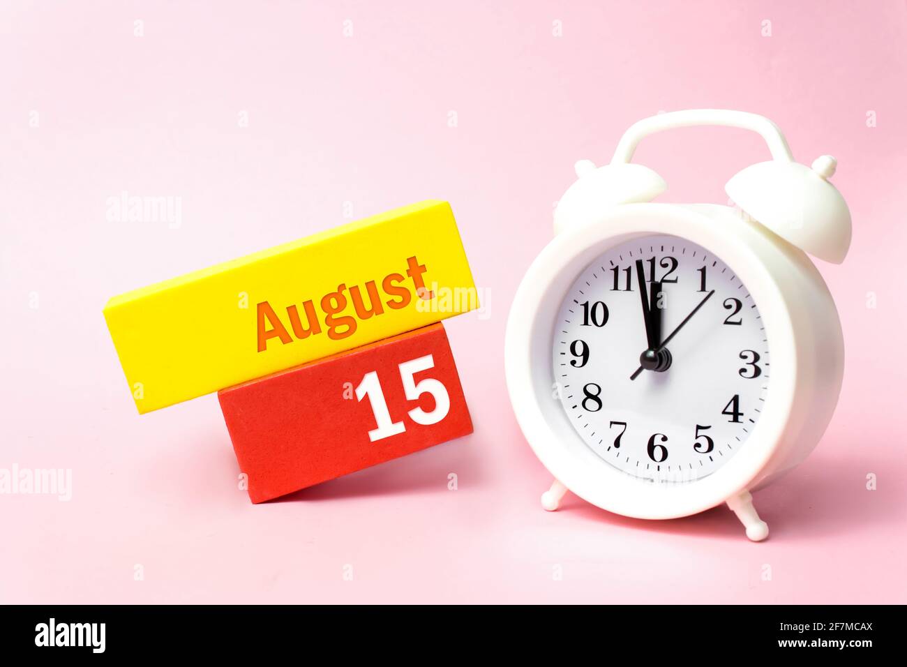 August. Tag 15 des Monats, Kalenderdatum. Weißer Wecker auf pastellrosa Hintergrund. Sommermonat, Tag des Jahres Konzept Stockfoto