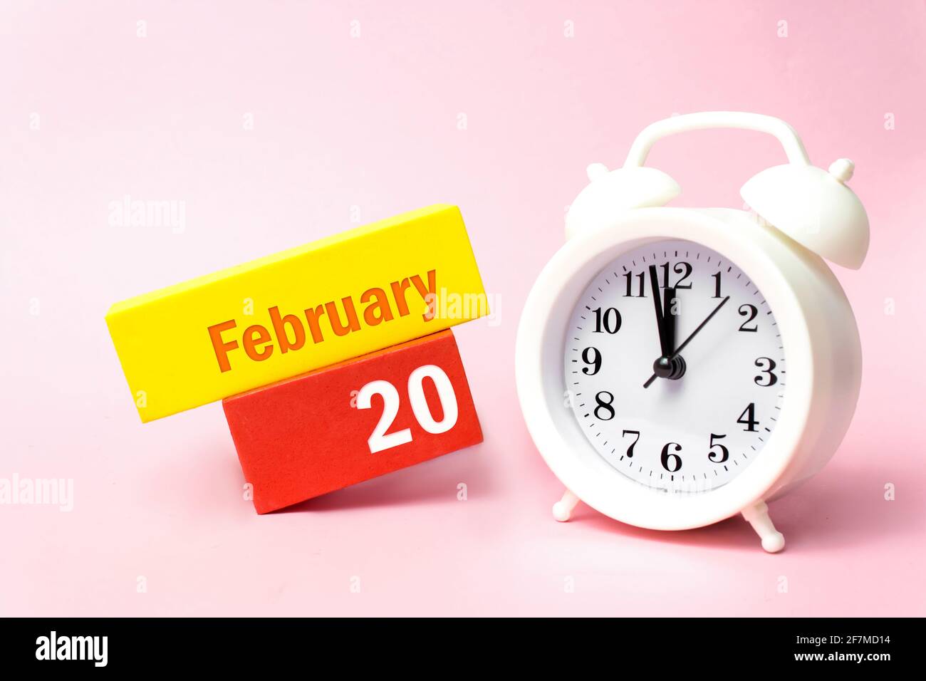 Februar. Tag 20 des Monats, Kalenderdatum. Weißer Wecker auf pastellrosa Hintergrund. Winter Monat, Tag des Jahres Konzept Stockfoto