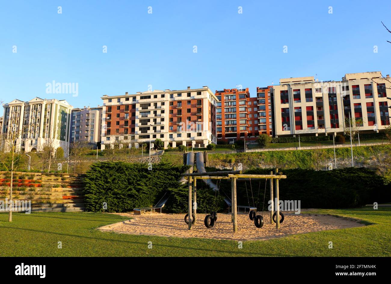 Gummireifen Schaukeln hing an einem Holzrahmen und Metallrohrrutschen mit natürlichem Sandboden Morgen Sonne Santander Cantabria Spanien Stockfoto