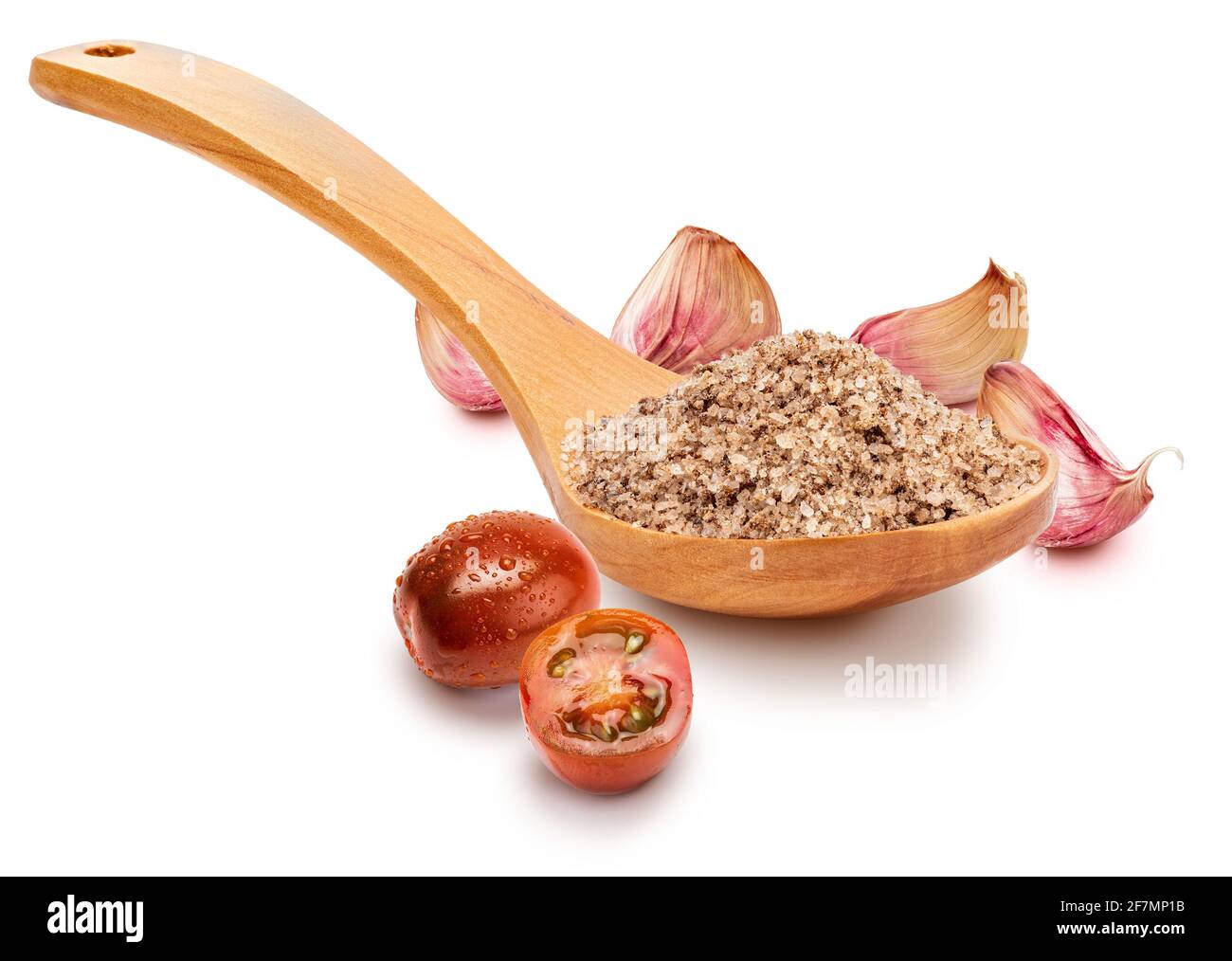 Feines weißes Salz mit Tomaten und Knoblauch in Holzlöffel (Sammlung von Salzsorten). Isoliert auf weißem Hintergrund. Rustikale Optik. Stockfoto