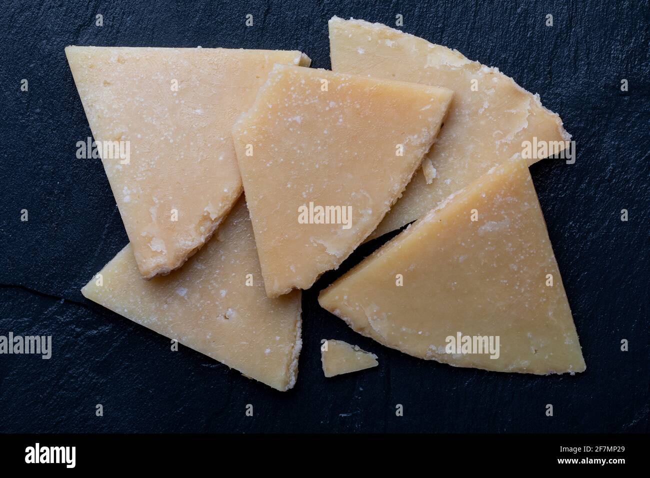 Ausgehärteter Schafskäse. Auf schwarzem Schiefer in Stücke schneiden. Vordergrund. Draufsicht. Stockfoto